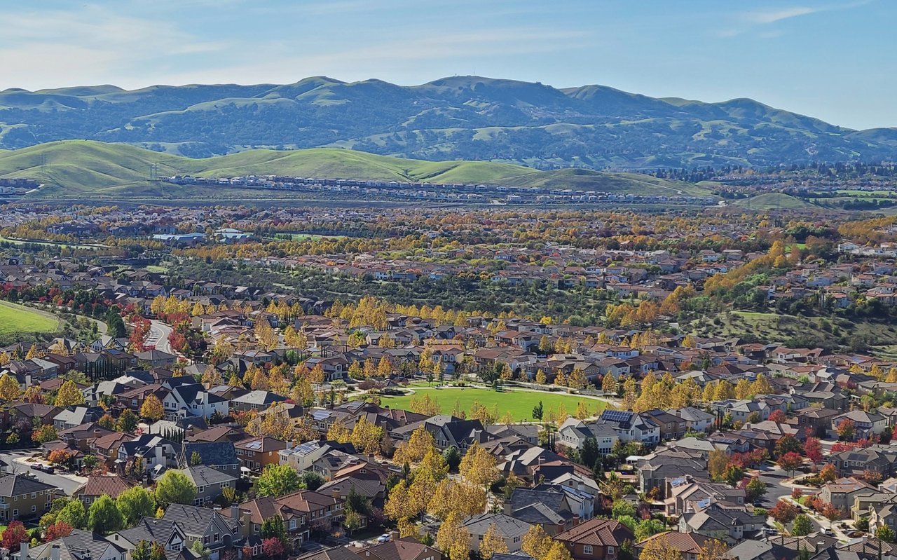 Suburban East Bay homes and autumn trees spread across a valley beneath rolling hills and mountains.