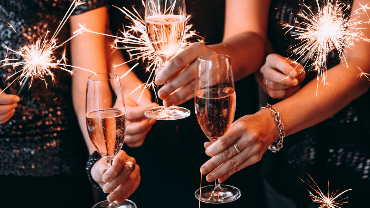 Guests clink champagne glasses while holding sparklers at a festive gathering.