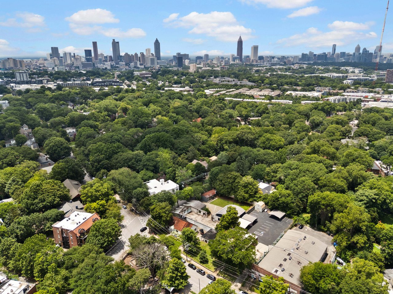 Aerial view of leafy Atlanta neighborhoods with the downtown skyline in the distance.