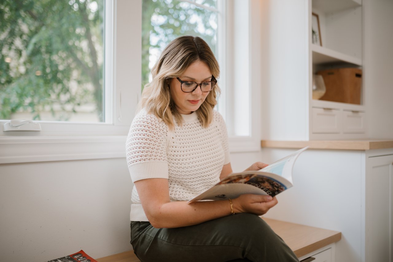 Cait Berry, a local Madison real estate expert with Insiders Realty, sitting by a bright window while carefully analyzing local Dane County housing market reports and data to build winning buyer strategies.