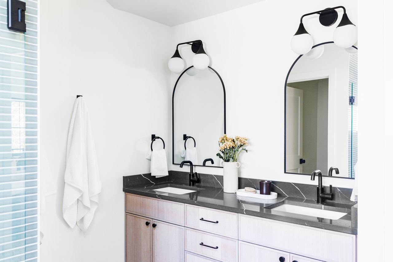 Primary Suite bathroom vanity with two sinks, black quartz counters and wood cabinets