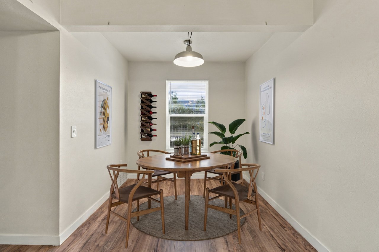 Dining area with a round wooden table, four chairs, and a window with blinds.