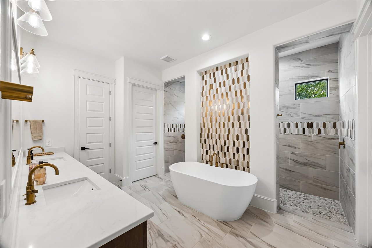 Bathroom with a freestanding soaking tub, double vanity, and marble-look walk-in shower.