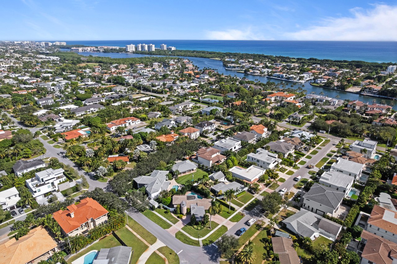 Aerial view of Boca Raton homes and palm-lined streets, with canals and the ocean beyond.