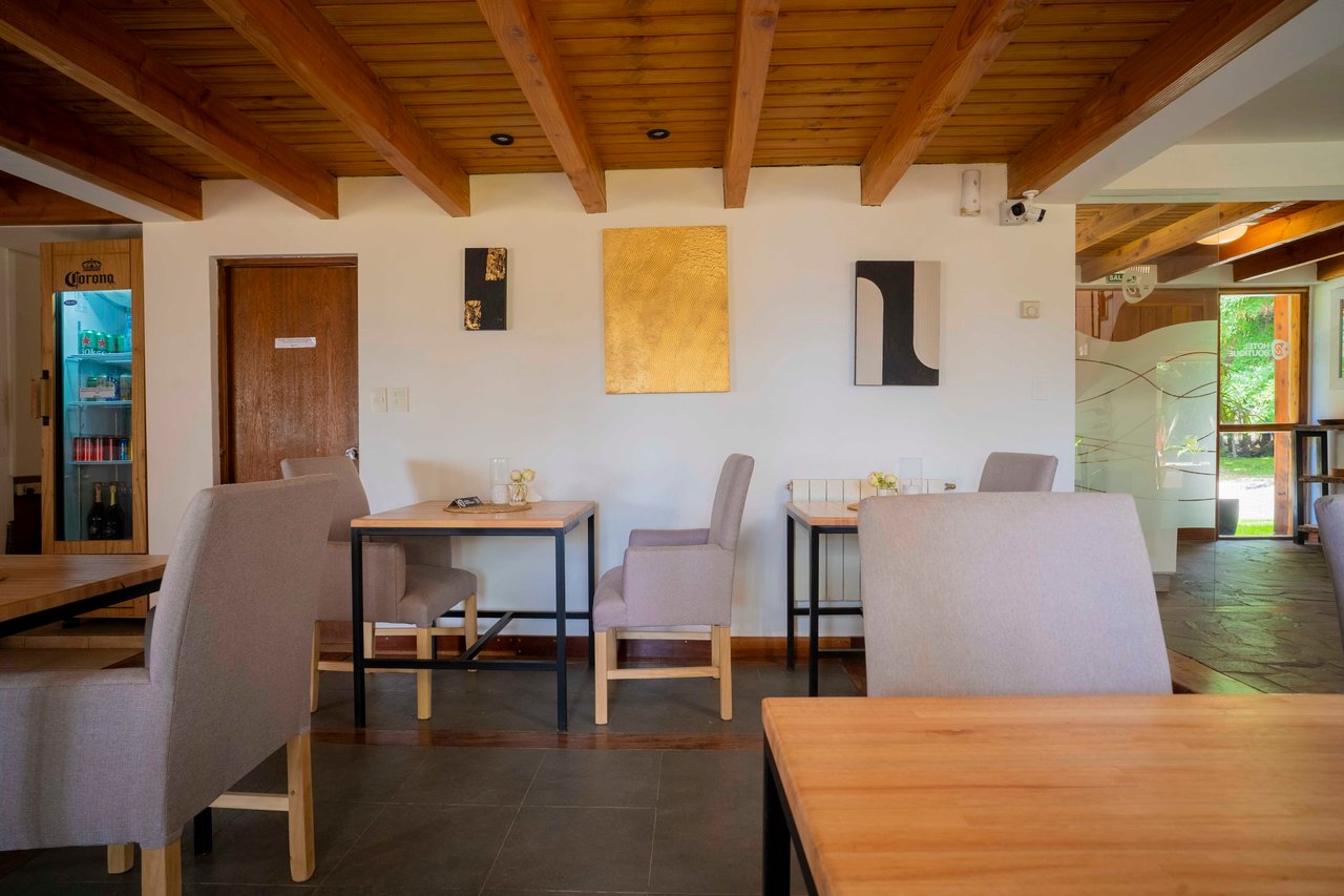 Hotel sitting area with upholstered chairs, wooden tables, and an exposed timber ceiling.