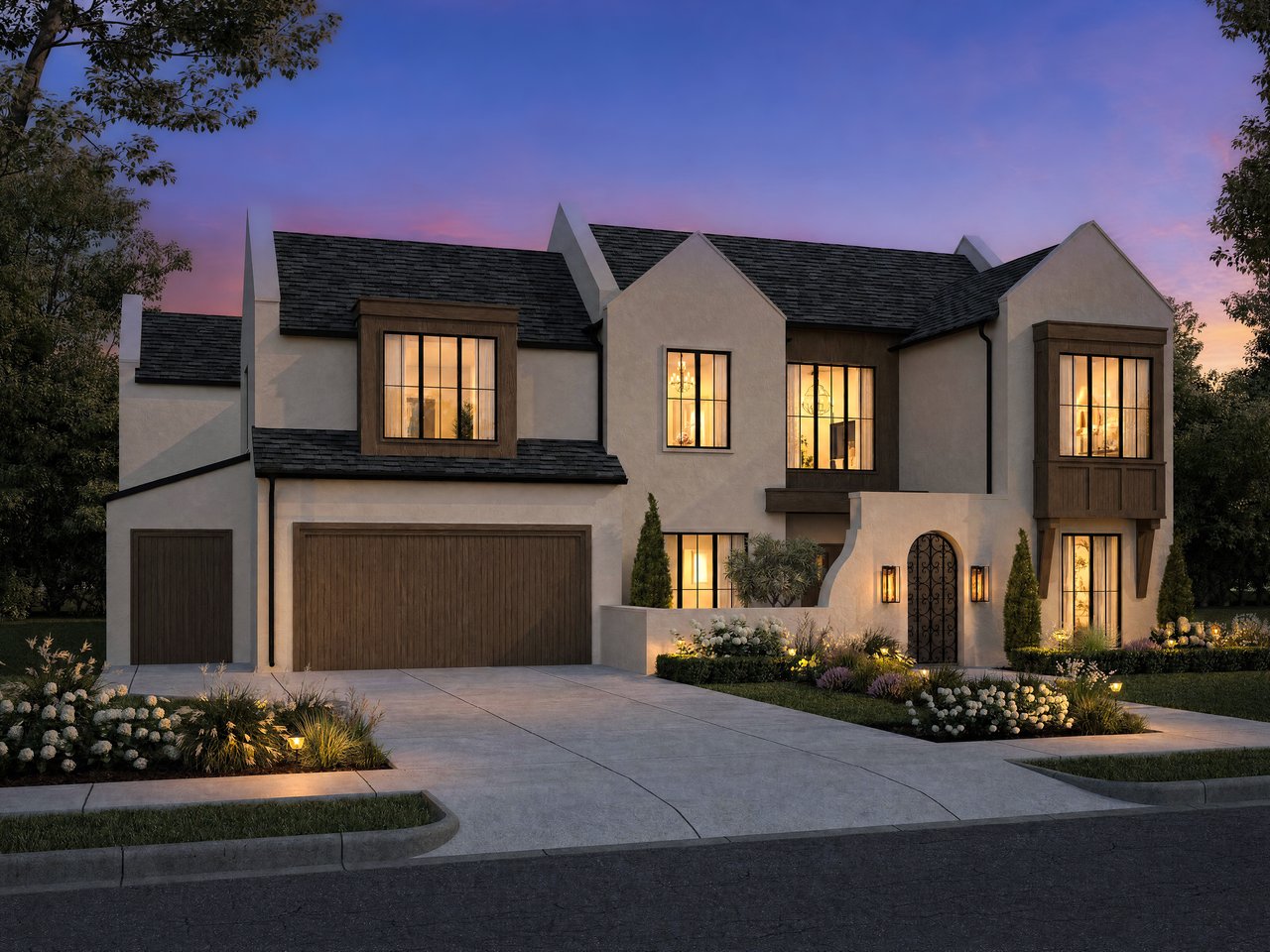 Two-story stucco house with dark roofs, an arched entry, landscaped gardens, and glowing windows at dusk.
