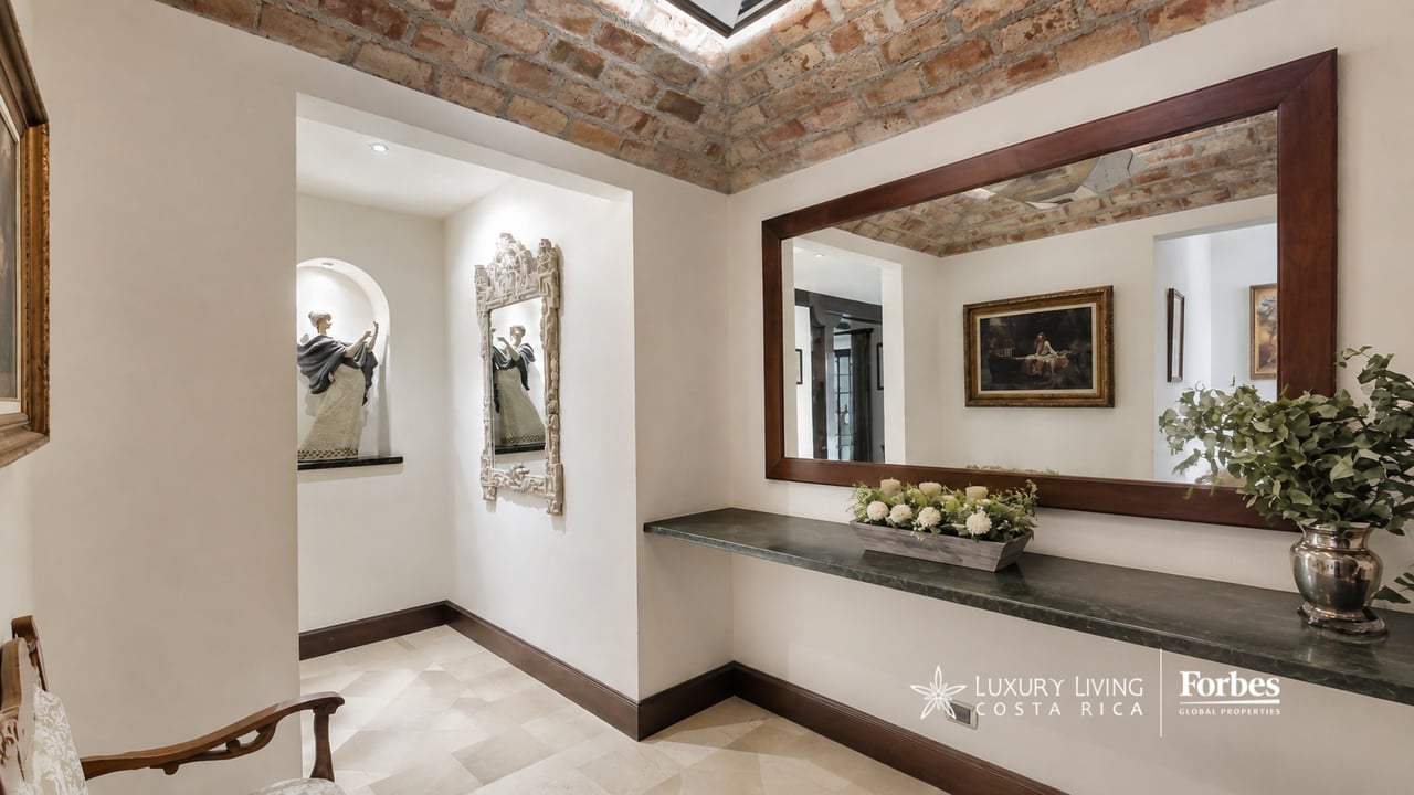 Entry hall with a stone console, large wood-framed mirror, and exposed brick ceiling.
