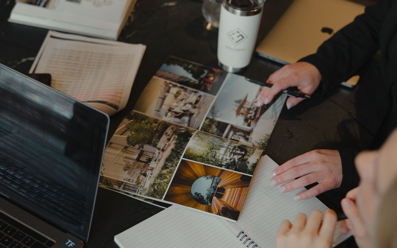 People review home photographs and take notes around a table.