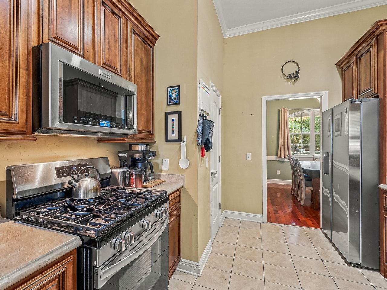 Kitchen with wood cabinets and stainless appliances, opening into a dining area.