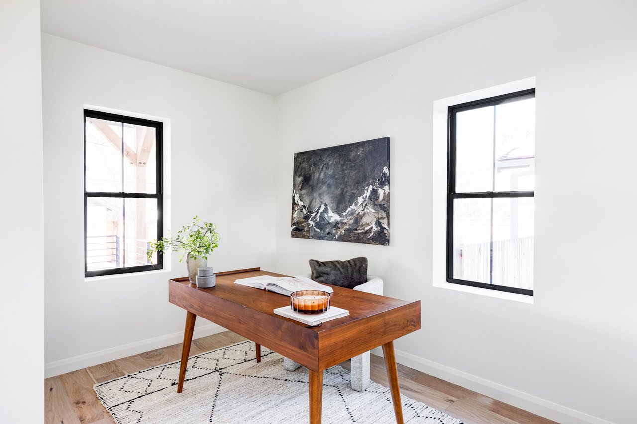 Bright home office with wooden desk, plush chair and white carpet