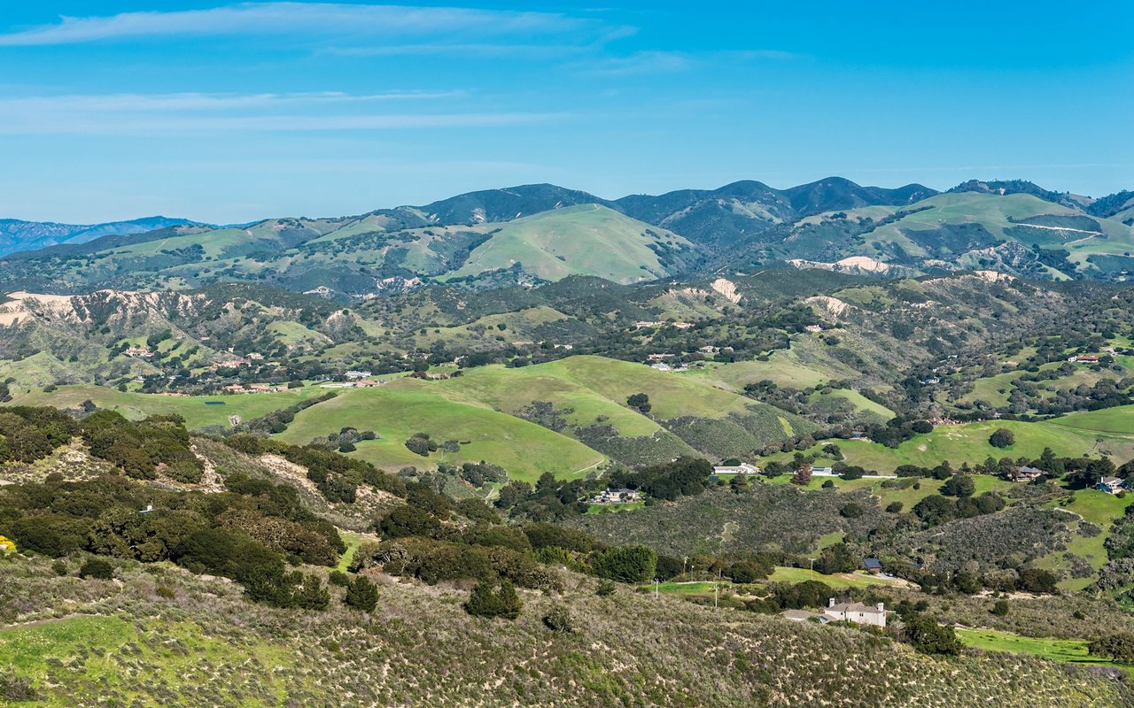 Rolling green hills and rugged countryside dotted with scattered homes.
