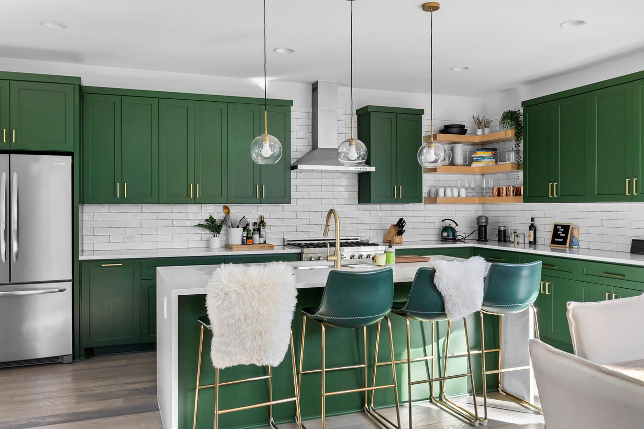 Kitchen at 404 Powell Cir Unit B in Austin's Dawson neighborhood, with hunter green cabinetry, a quartz-topped island, and brass pendant lighting.