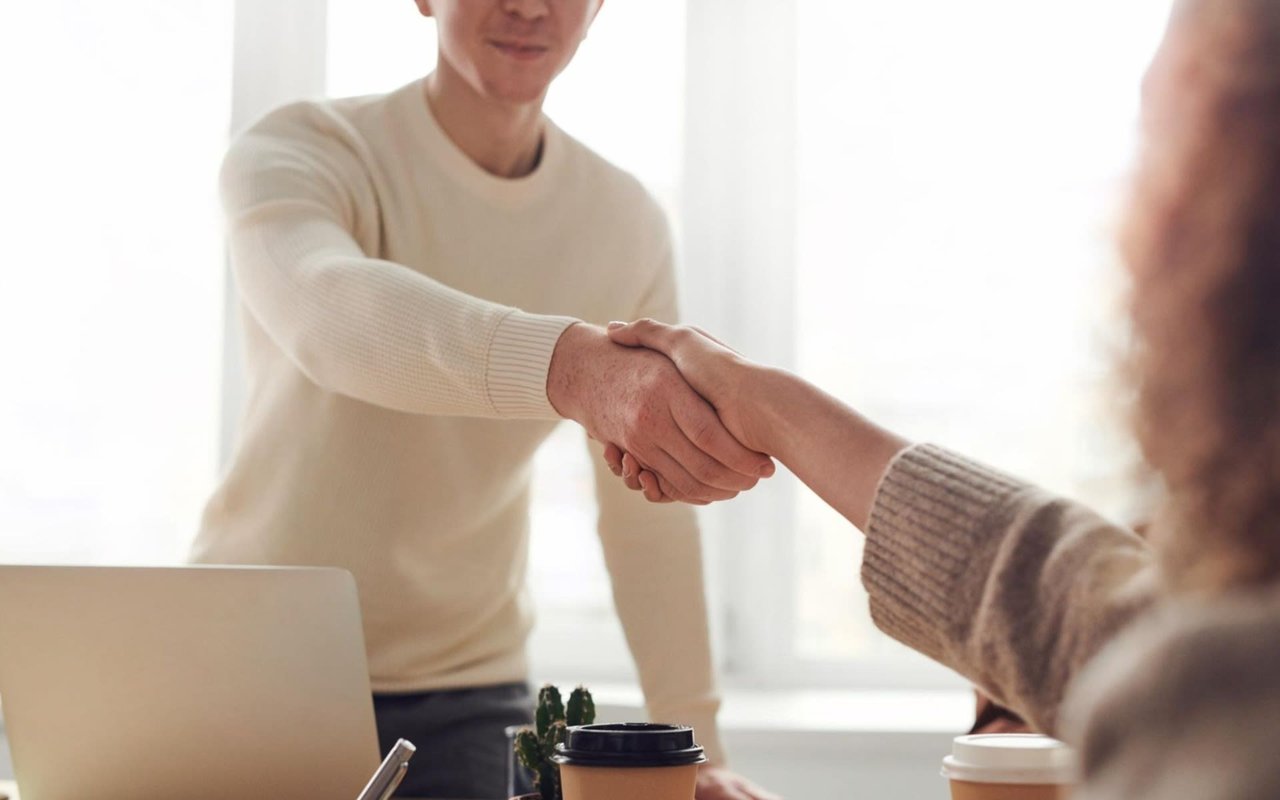 A real estate agent shaking hands with a client to finalize a home purchase contract agreement during a successful meeting.