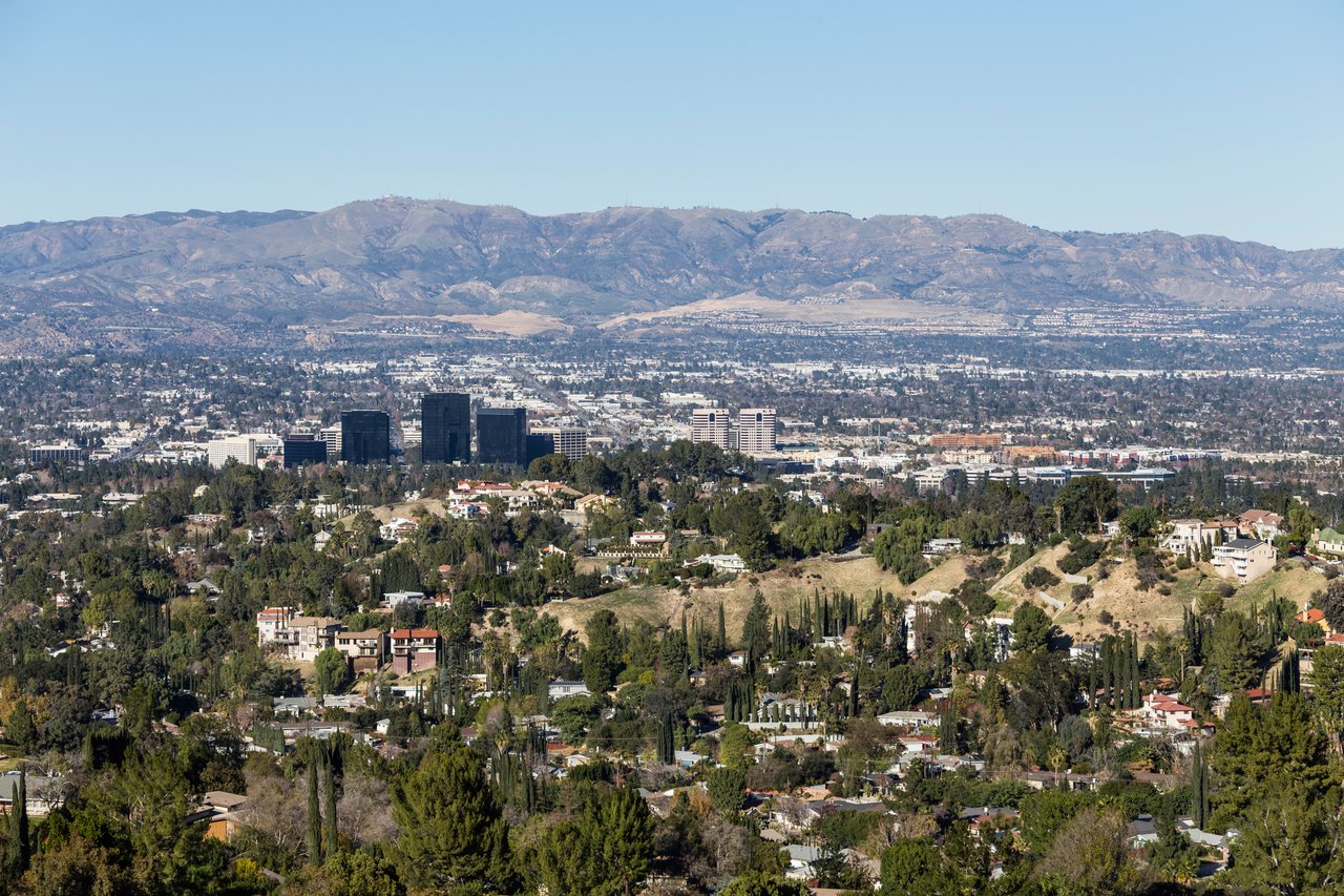 Panoramic view over a tree-lined valley toward a mountain range.