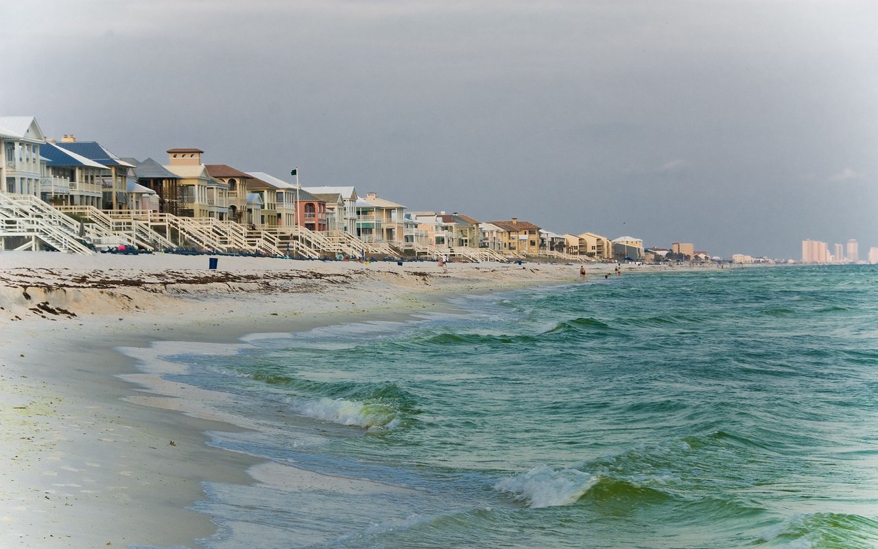 Gulf Coast beach with raised beachfront homes lining the shore.