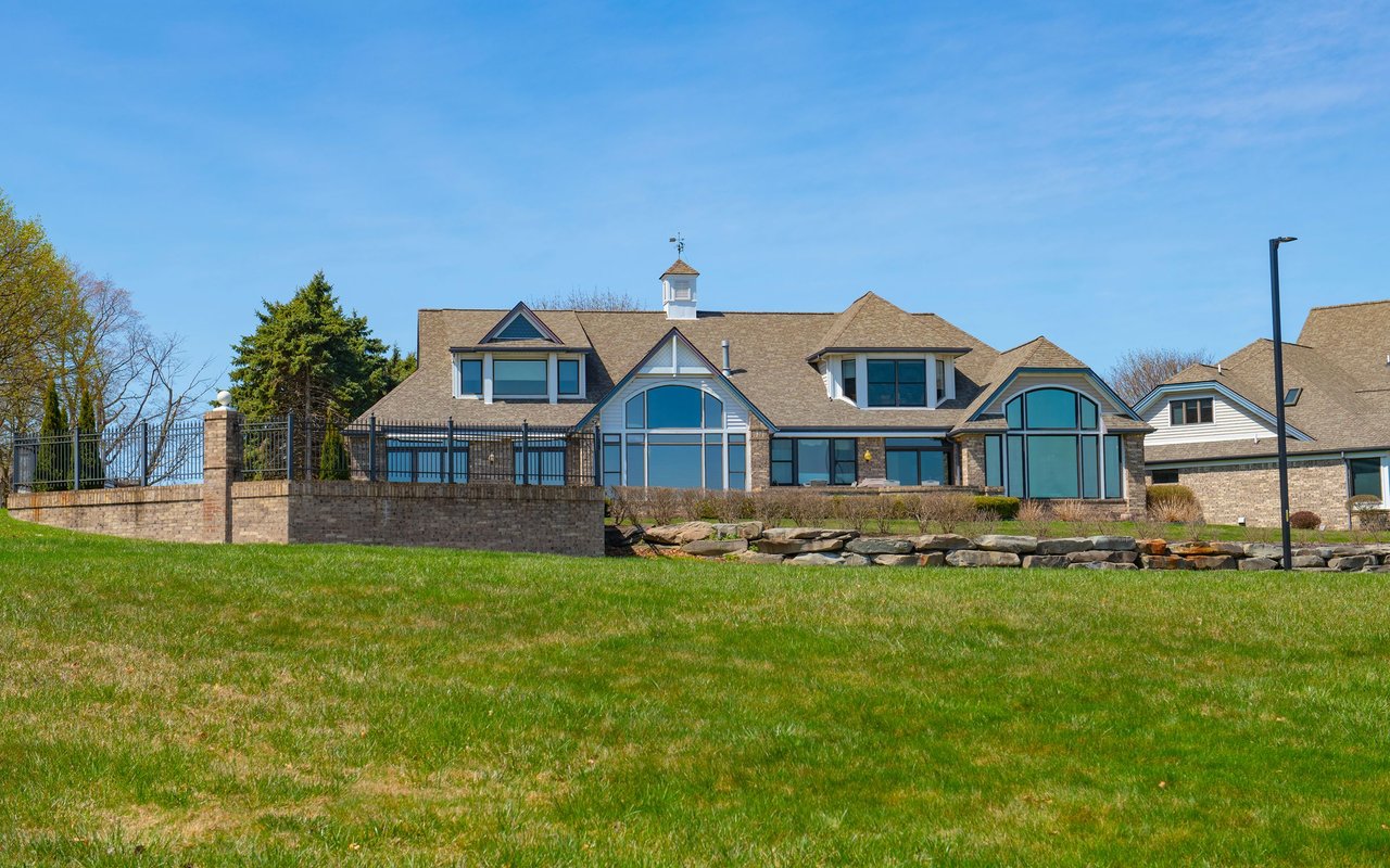 Large stone building with arched windows, a fenced patio, and a broad lawn.