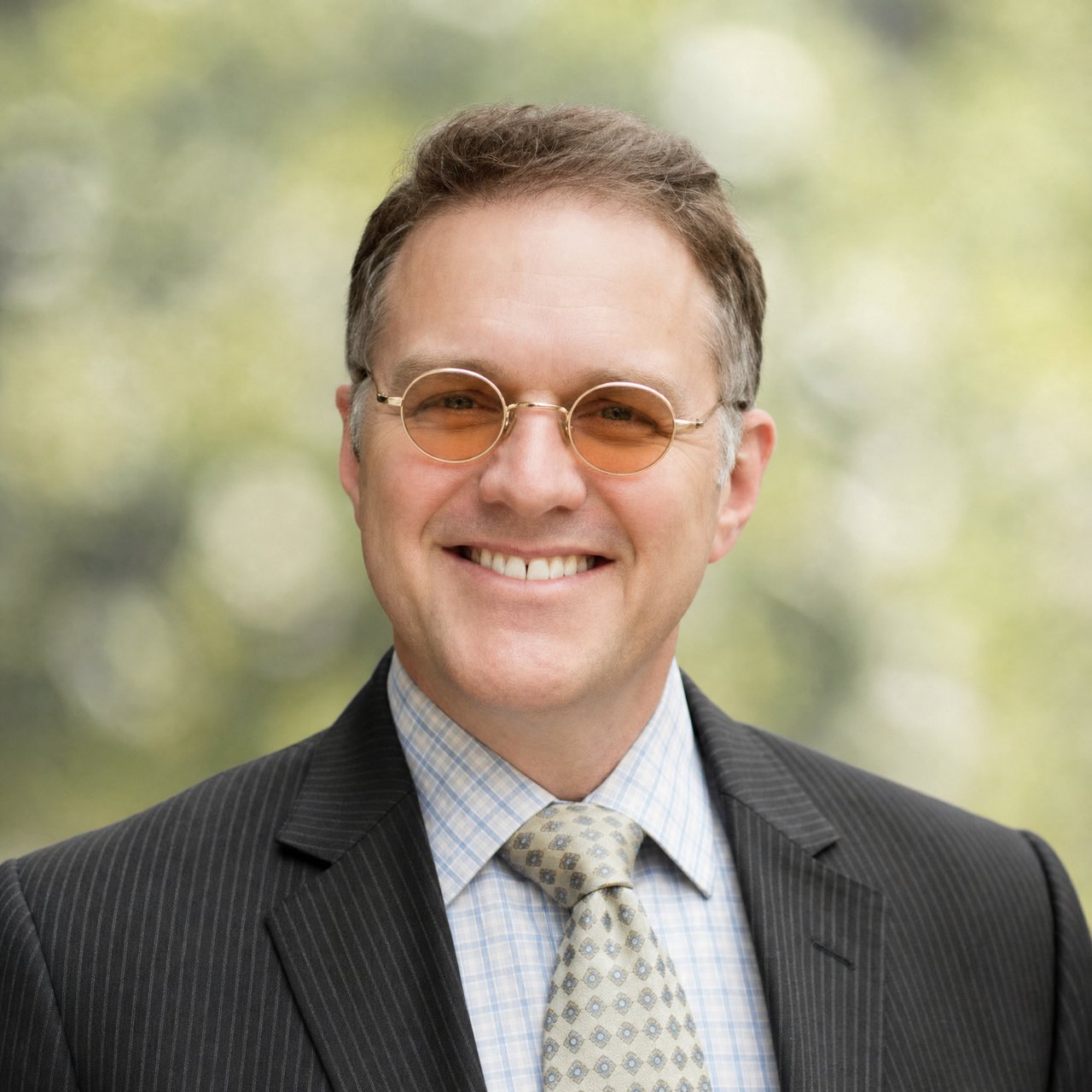 Philip Freedman wearing round glasses and a pinstripe suit