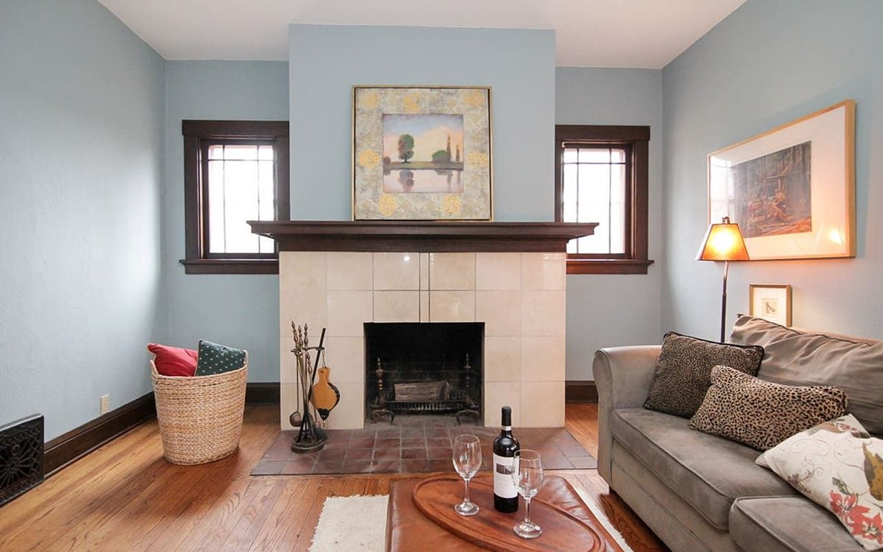 Living room with a tiled fireplace, dark wood mantel, and gray sofa.