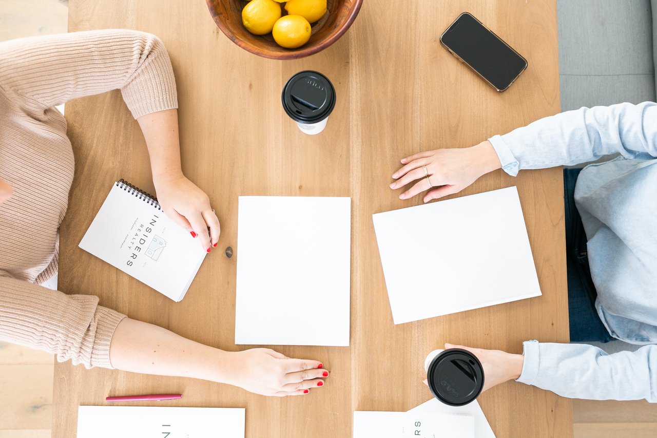 Two people reviewing documents across a table while working out signing authority for a home sale.