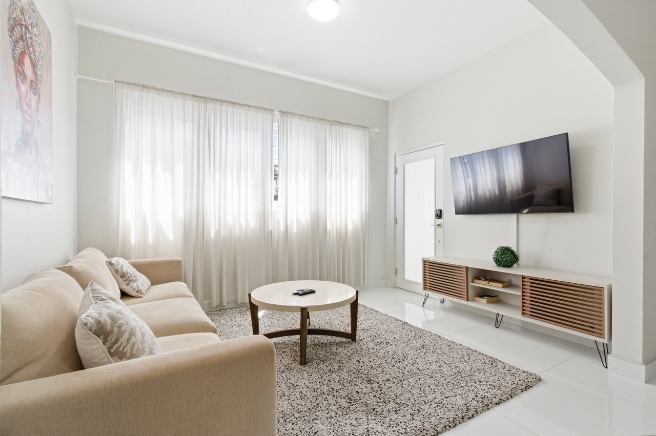 Living room with beige sofa, round coffee table, and wall-mounted television.