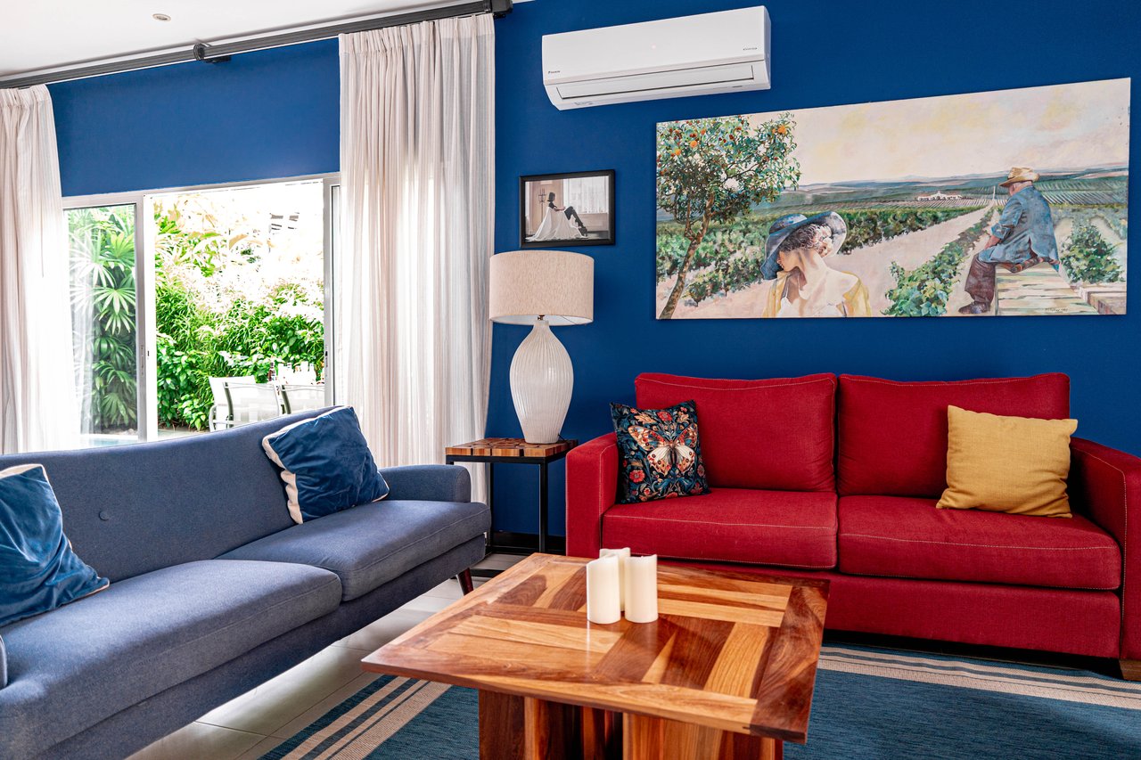 Living room with blue walls, red and gray sofas, and a sliding door facing greenery.