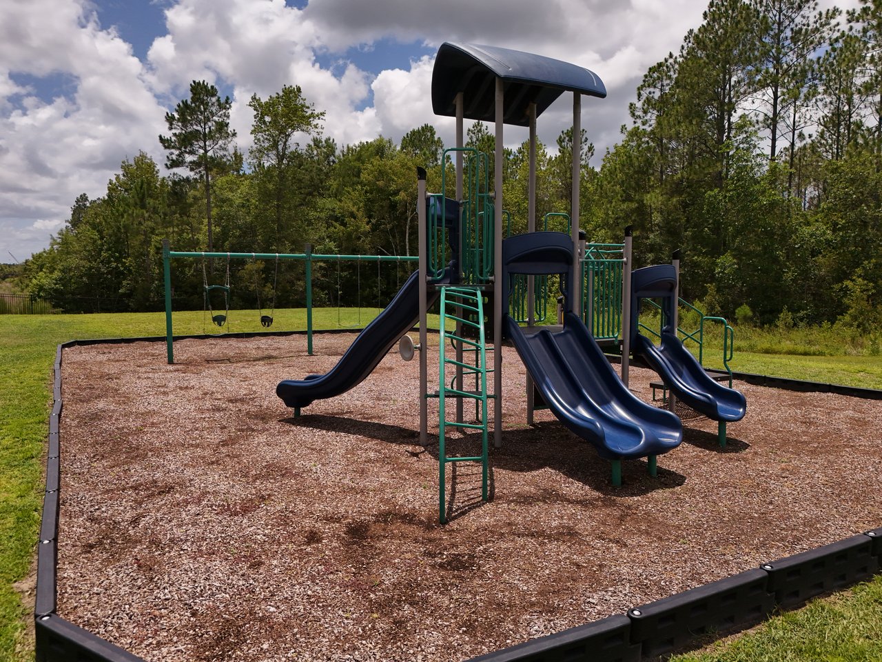 Community playground with a covered climbing structure, slides, and swings.