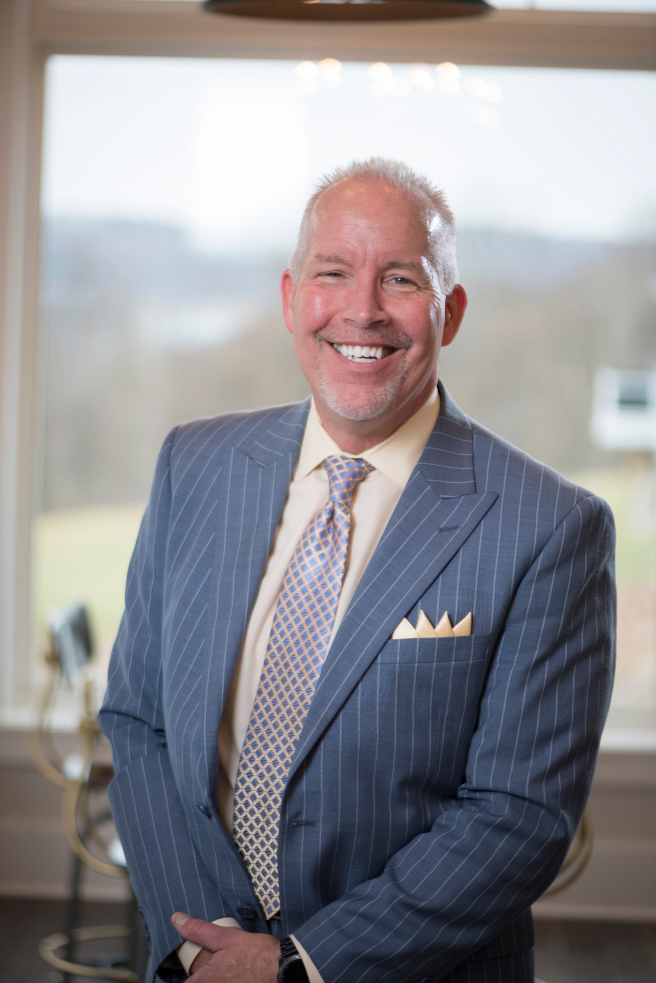 Mike Netzel smiling in a blue pinstripe suit and patterned tie.