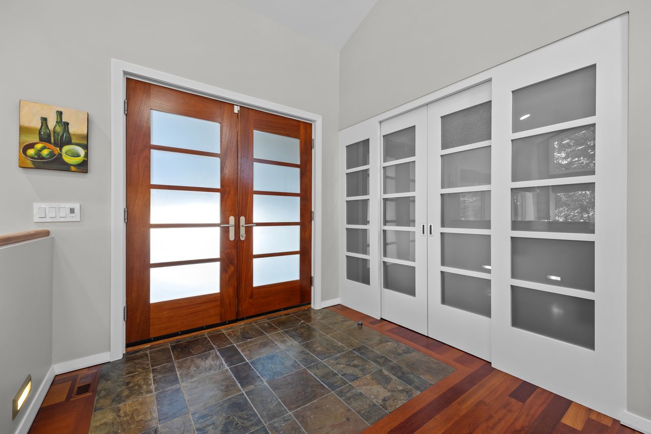 Entry foyer with double wood-and-glass doors, white glass-panel closet doors, and slate tile flooring.