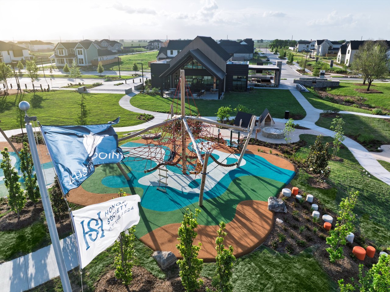 Austin Point playground with a rope climbing structure, colorful play surface, and modern clubhouse.