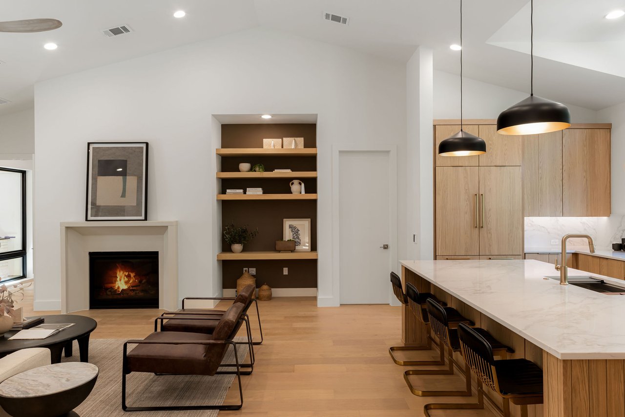 Great room at 1001 Bluebonnet Ln (Zilker, Austin) with a vaulted ceiling, gas fireplace, and wide-plank white oak floors, open to the kitchen. Built by Rivendale Homes.