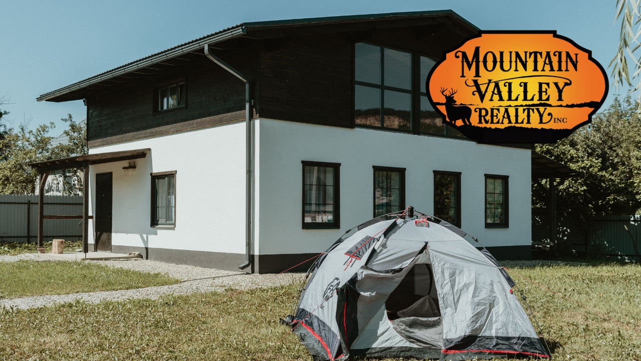 Two-story white-and-dark home with a gray tent pitched on the lawn.