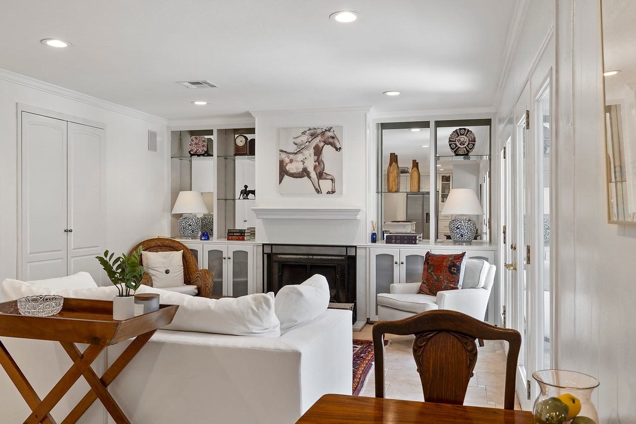 Living room at 2404 Westover Rd in Tarrytown, Austin, with a fireplace, built-in bookshelves, a horse painting, and a wicker armchair.