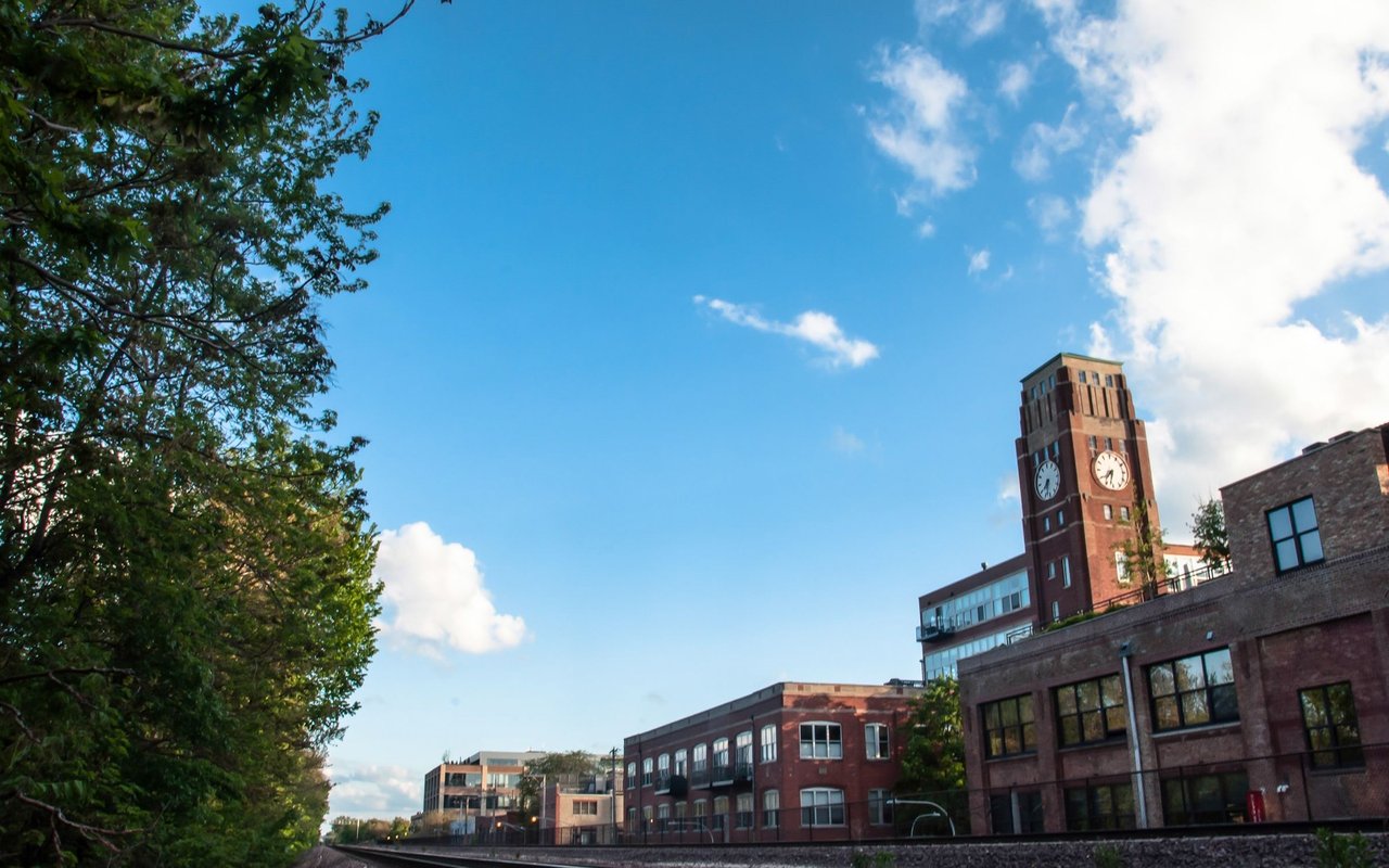 Ravenswood streetscape with brick buildings, a clock tower, and leafy trees.