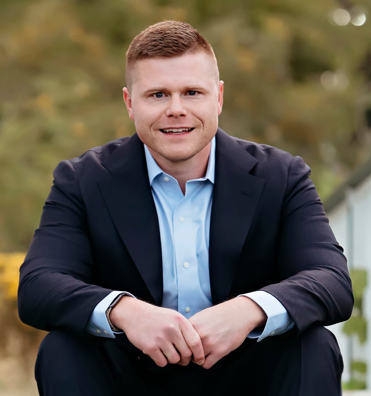 Jonathan Thomas seated outdoors in a dark suit and light blue shirt.