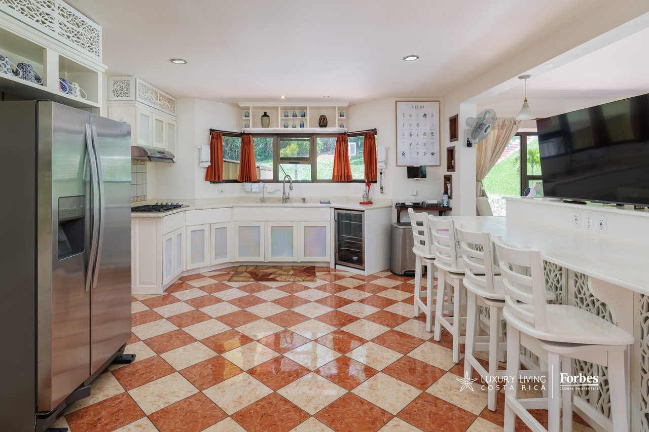 Kitchen with white cabinetry, stainless steel refrigerator, and a long breakfast bar over checkered tile floors.