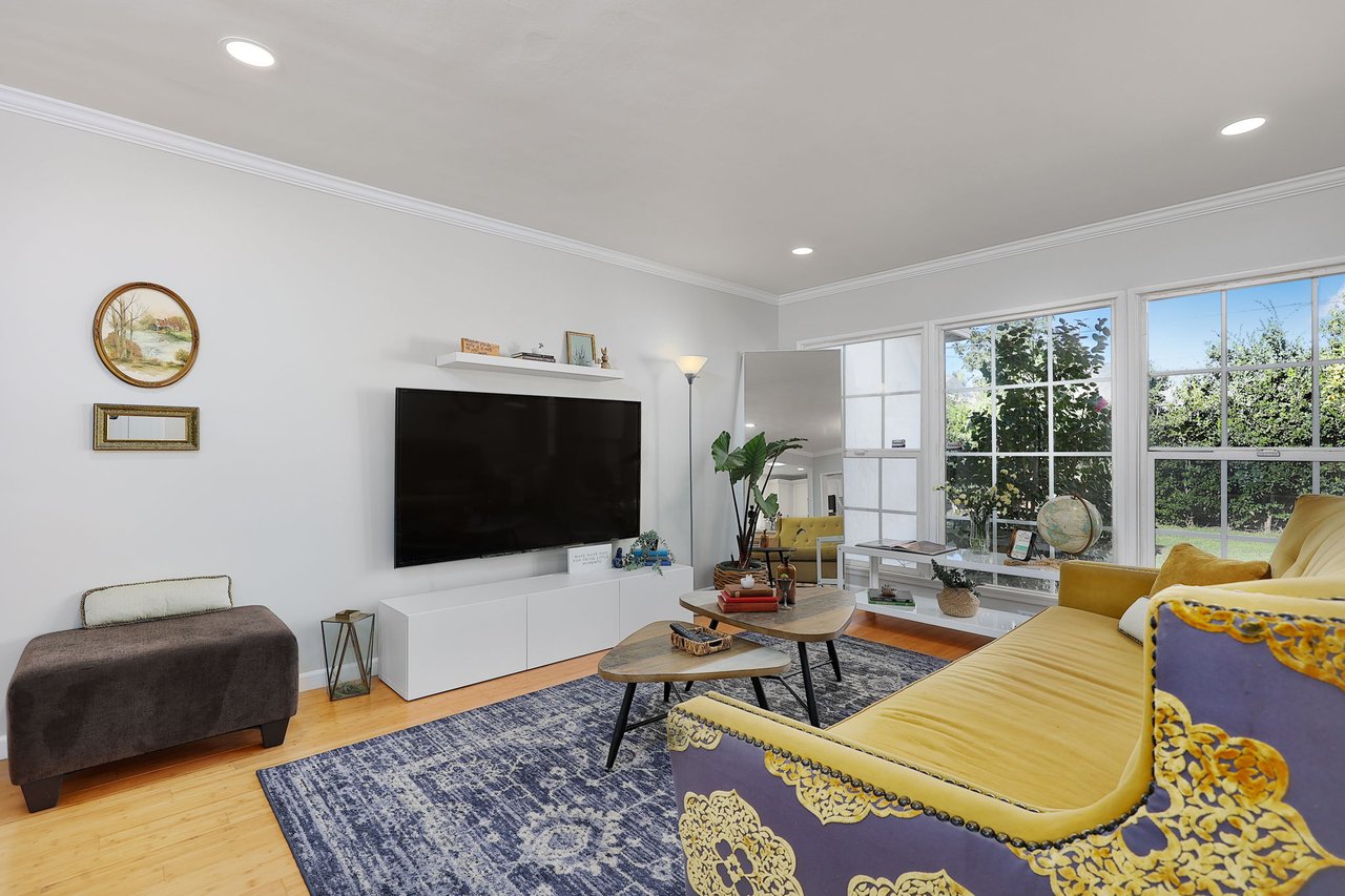 Bright living room at 17049 Baltar St with mounted flat-screen TV, bamboo flooring, and natural light