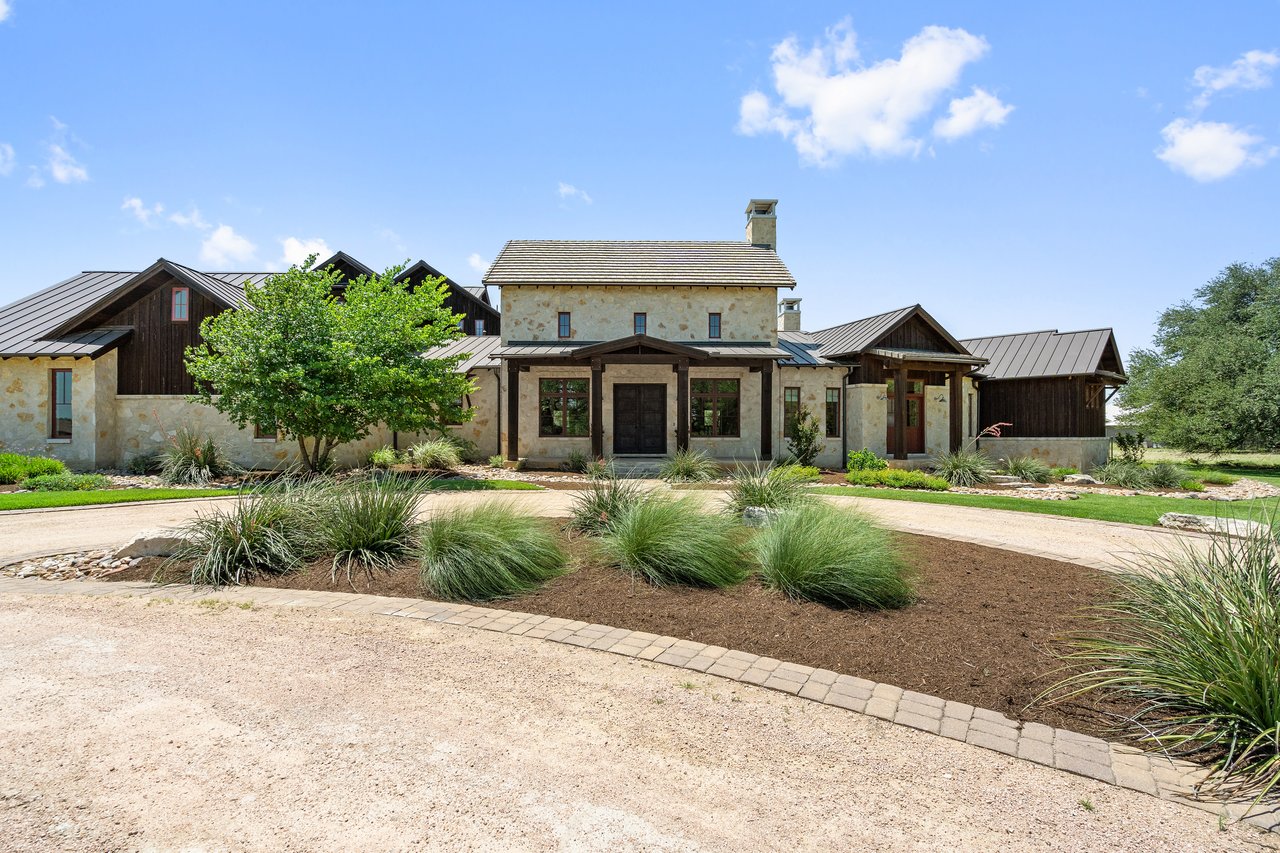 Daytime front elevation of 335 Winning Colors in Key Ranch at the Polo Club, designed by Design Visions of Austin, with a circular drive and native landscaping.