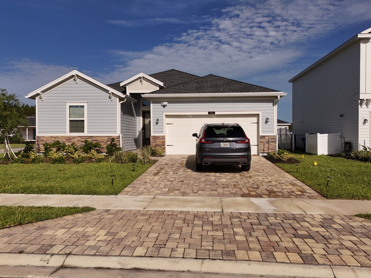 Gray single-story home with a stone-accented facade, attached garage, and car in the driveway.