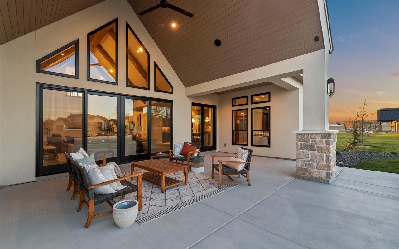 Covered back patio looking in towards the house - cream-colored stucco exterior and black windows