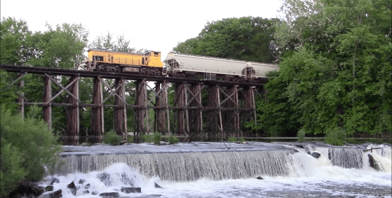 Train crossing a wooden trestle bridge over a waterfall in Hamilton, Michigan.