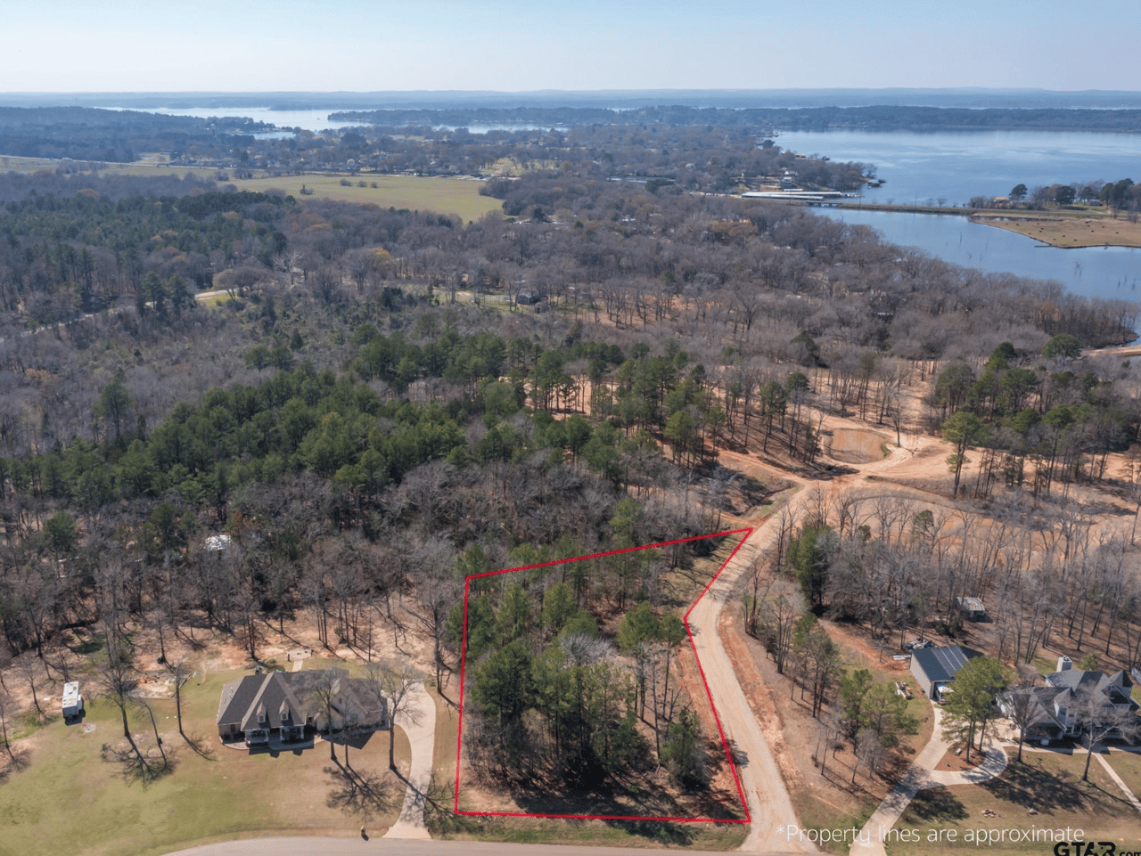 Alt text: "Aerial view of wooded corner lot for sale at 21324 Gatlinburg Road, Bullard TX in the Blue Ridge subdivision, with property lines marked and Lake Palestine visible in the background — East Texas land near Lake Palestine.