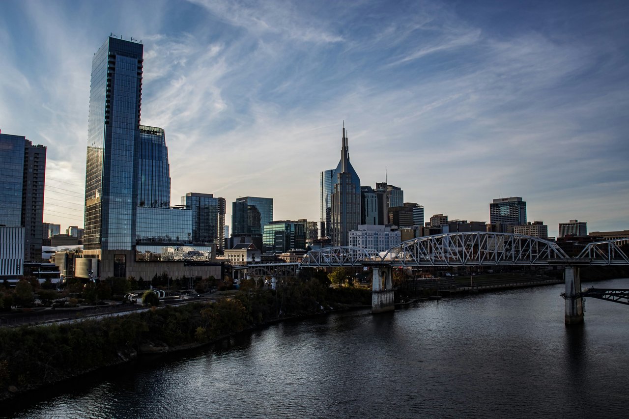 Nashville skyline and steel truss bridge over the river at golden hour.