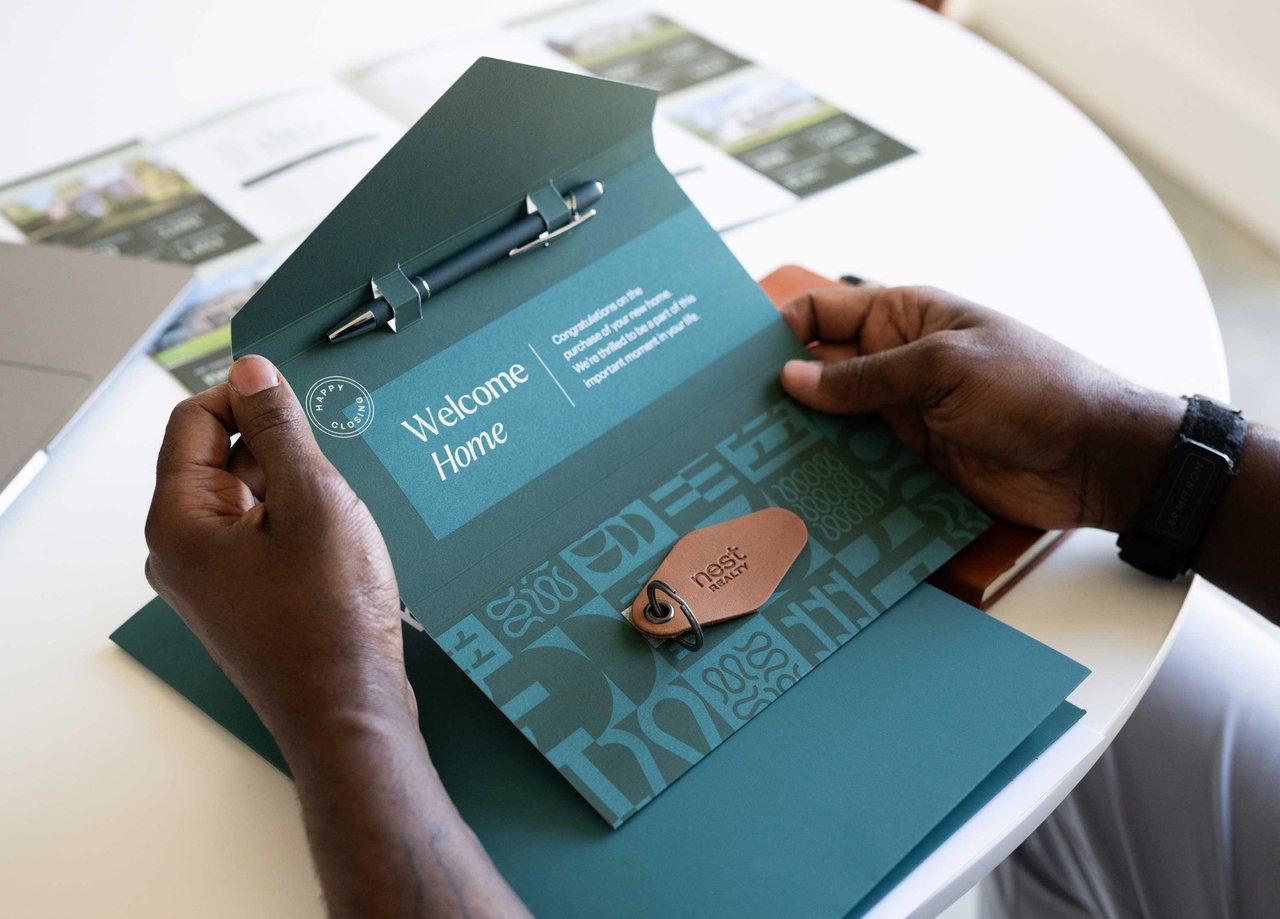 client opening their closing gift with a pen and Nest Realty keychain