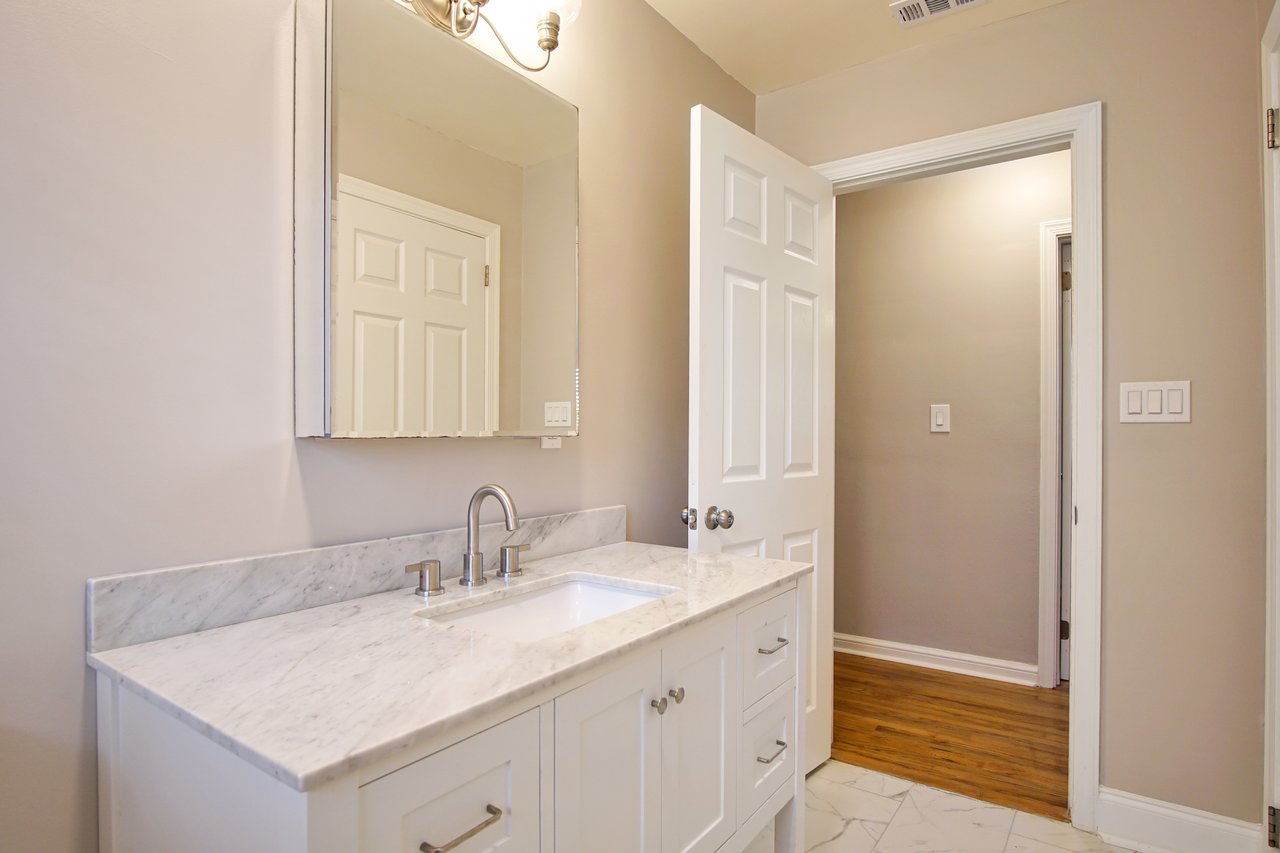 A modern bathroom featuring white cabinets and an elegant marble countertop, showcasing a clean and sophisticated design.