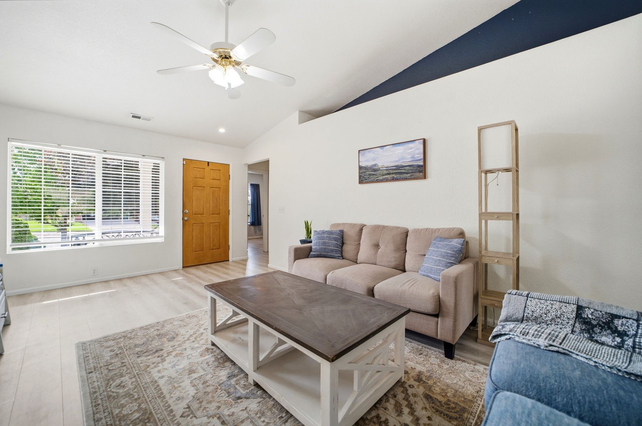 Living room with vaulted ceiling looking at entry and leading to bedrooms and bathroom