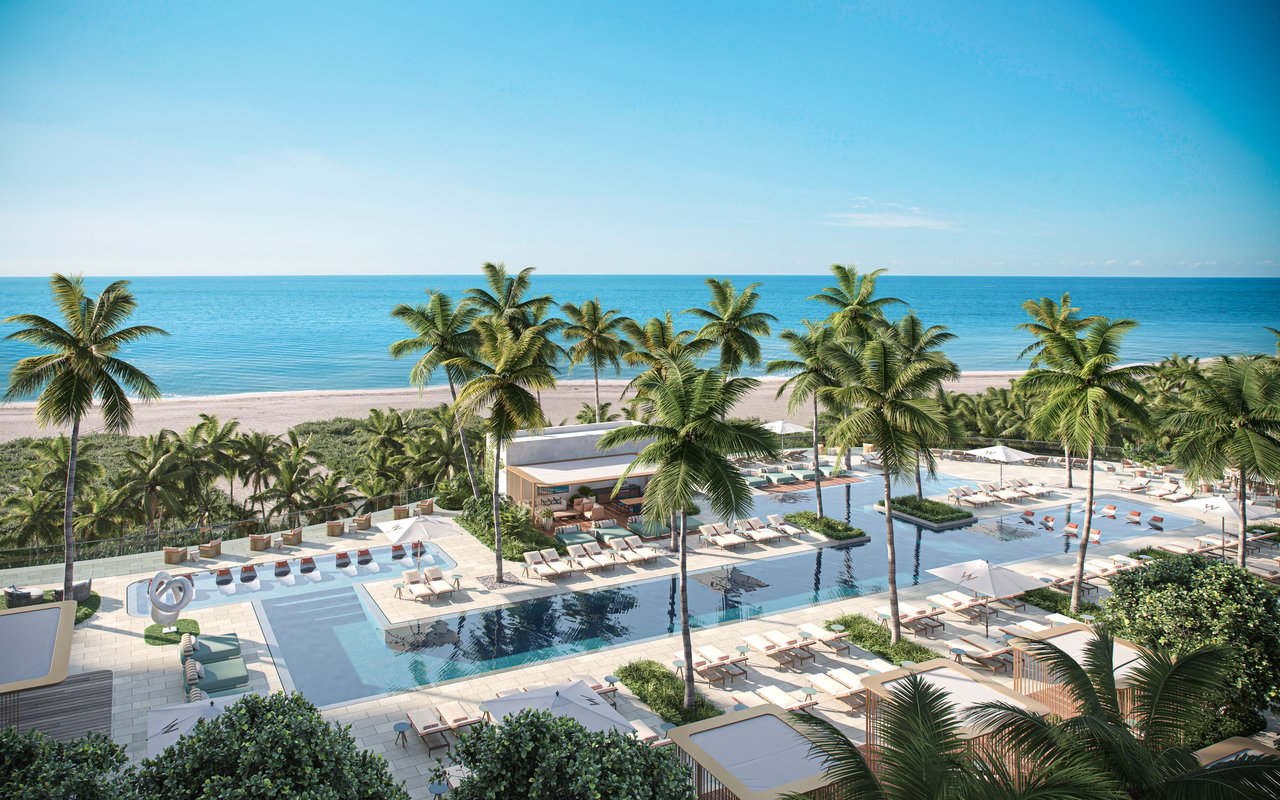 Beachfront resort pool deck with palm trees, lounge chairs, and ocean views.