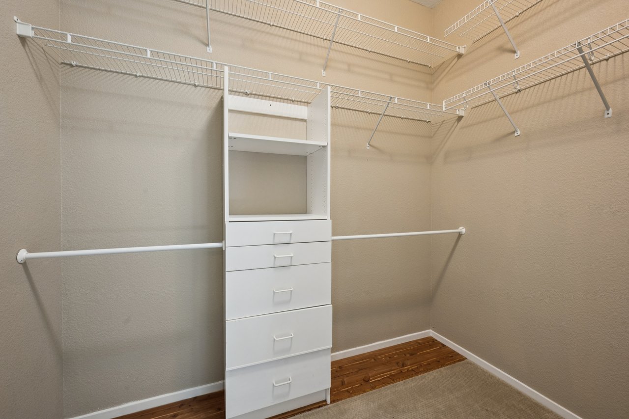 Walk-in closet with wraparound wire shelving and a central white drawer unit.