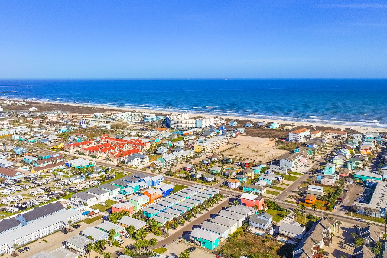 Aerial view of a coastal town, with colorful homes between the neighborhood and the ocean.