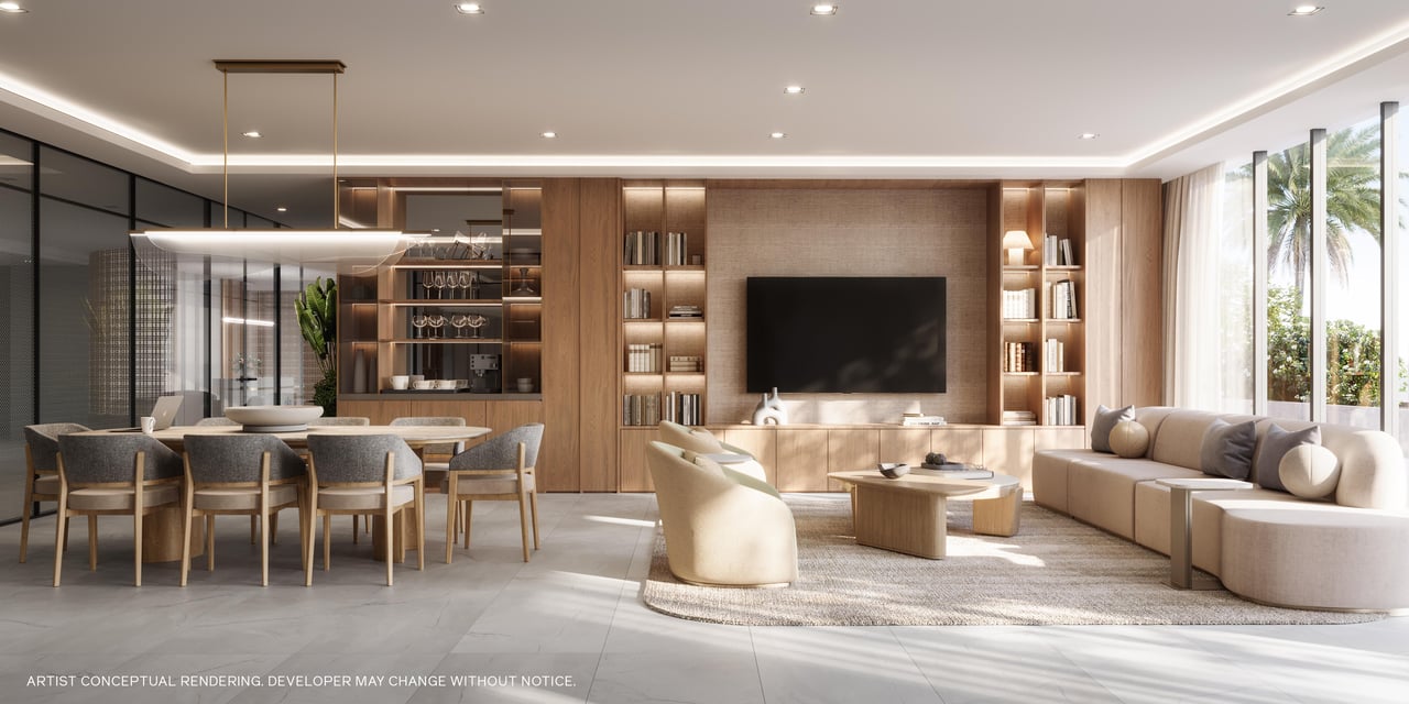 Open-plan living and dining room with warm wood cabinetry, a sectional sofa, and palm views through tall windows.