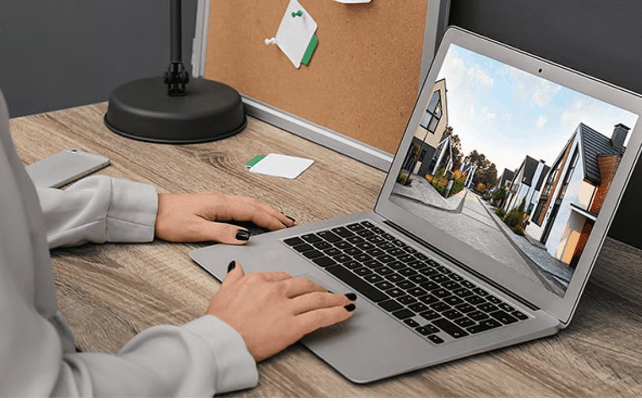 Person viewing modern townhouses on a laptop at a desk.